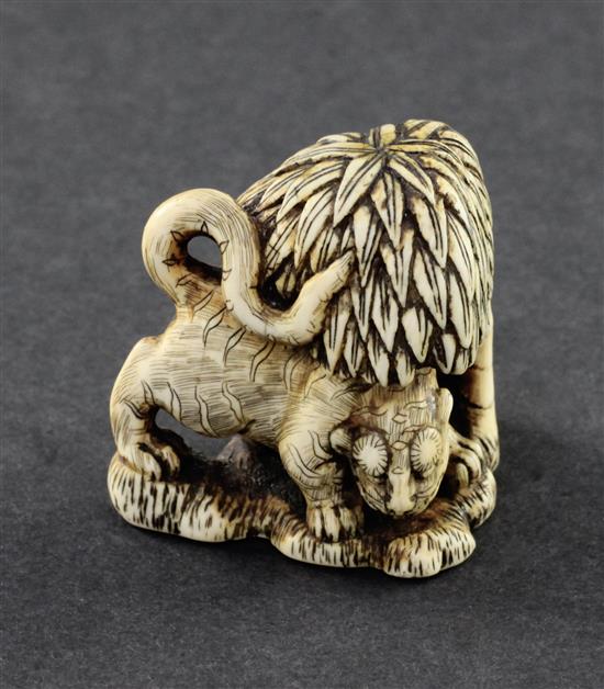 A Japanese stained ivory netsuke of a tiger crouching beneath a tree, 18th / 19th century, 4.2cm.